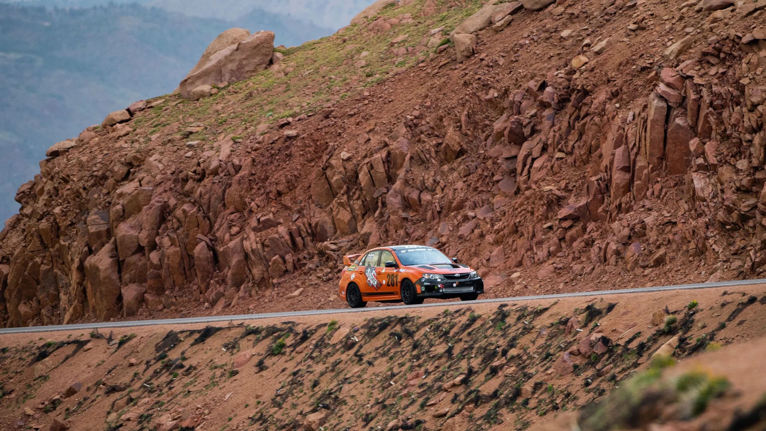 The #281 kicking up dust through a red-rock switchback on race day
